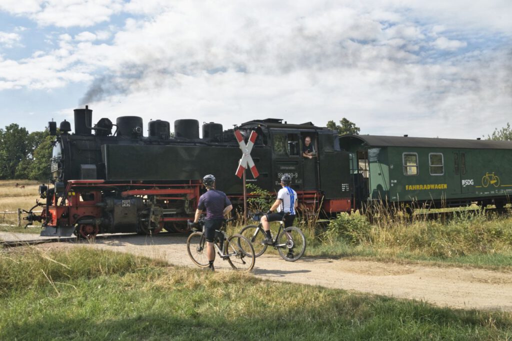 Gravel bikers wait at crossing of Loessnitz ground train in Saxony Germany