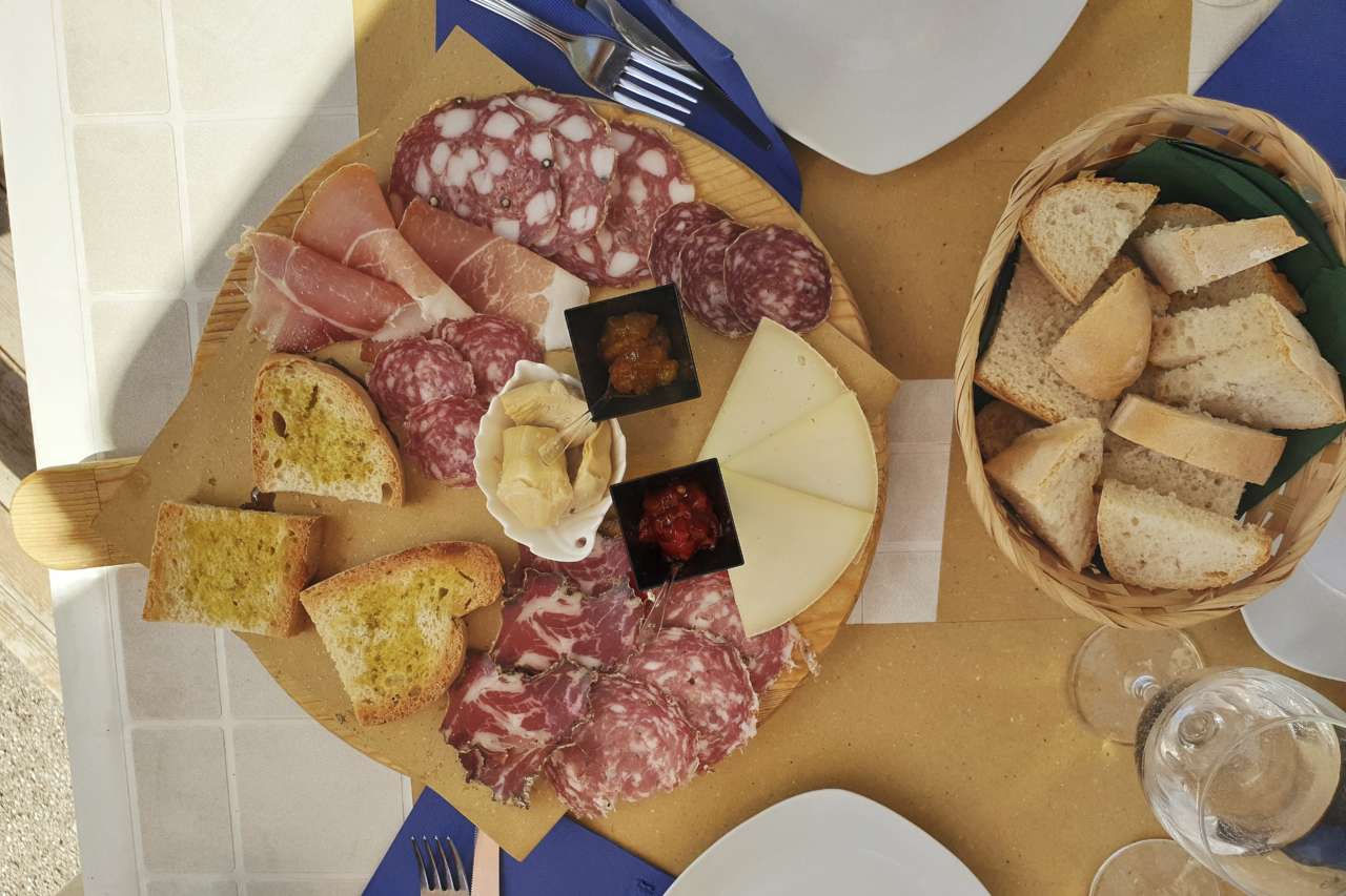 Toskanisches Antipasti mit verschiedenen Salami-, Schinken- und Käsesorten sowie Brot
