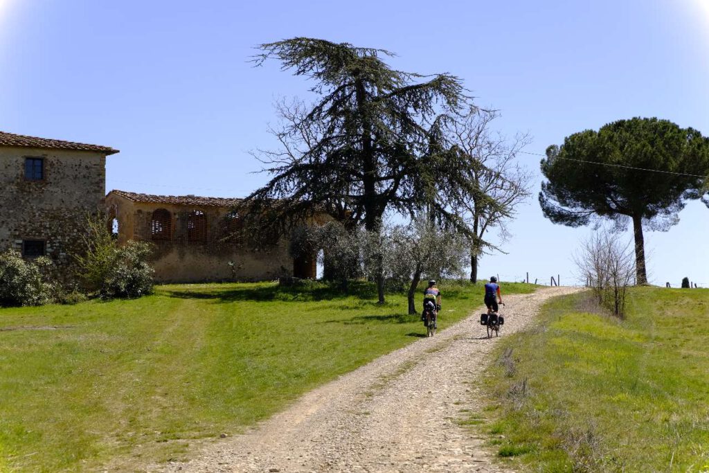 Gravelbiker fahren an einem alten Bauernhof in der Toskana entlang