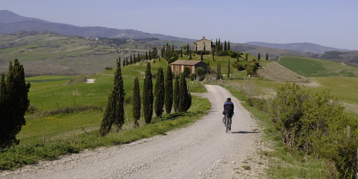 Gravel biker on gravel road to a villa in Tuscany, Italy