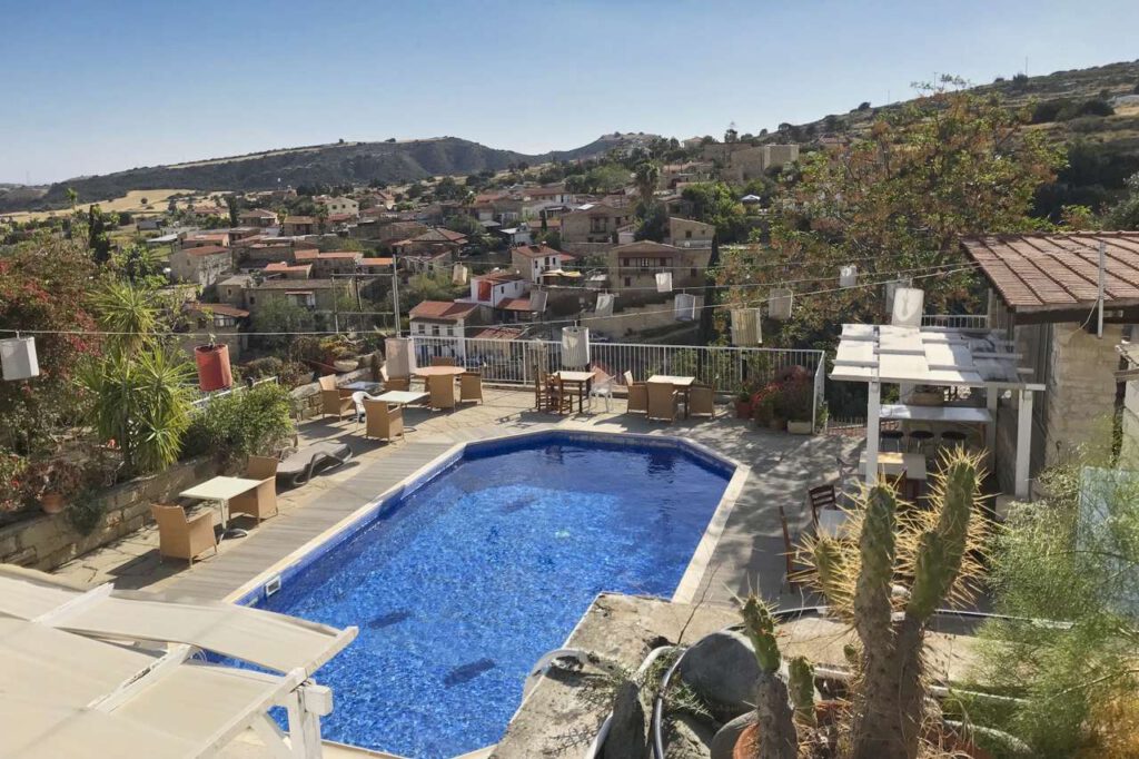 View of the pool area of a hotel in Tochni, Cyprus. In the background a hill with residential buildings and other accommodations in Tochni.